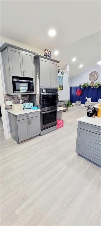 kitchen with appliances with stainless steel finishes, light hardwood / wood-style floors, and gray cabinetry