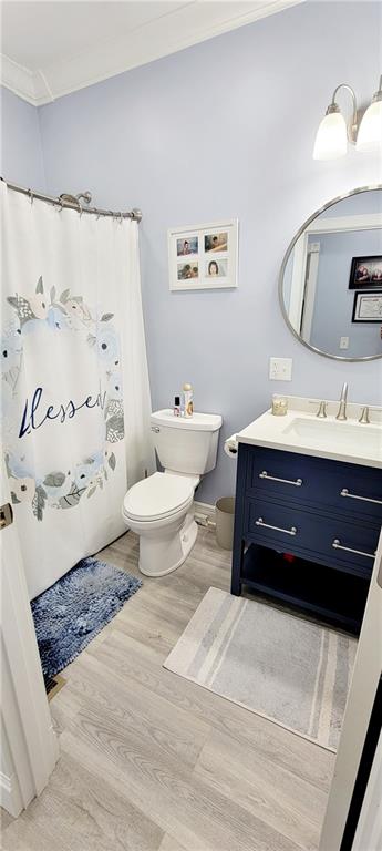 bathroom with toilet, hardwood / wood-style floors, vanity, and crown molding