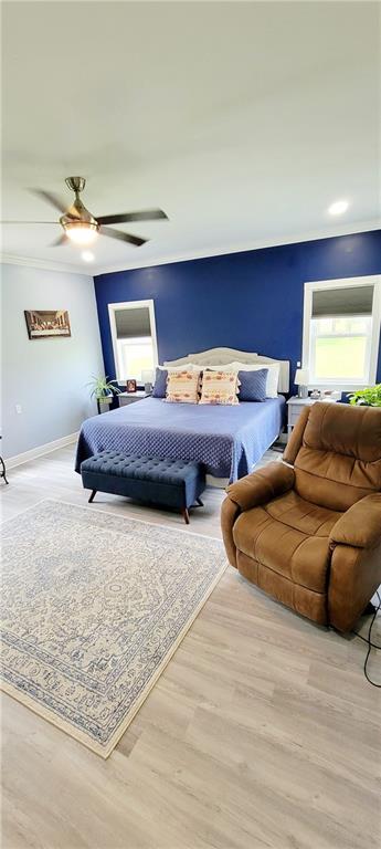 bedroom with ornamental molding, ceiling fan, and light hardwood / wood-style flooring