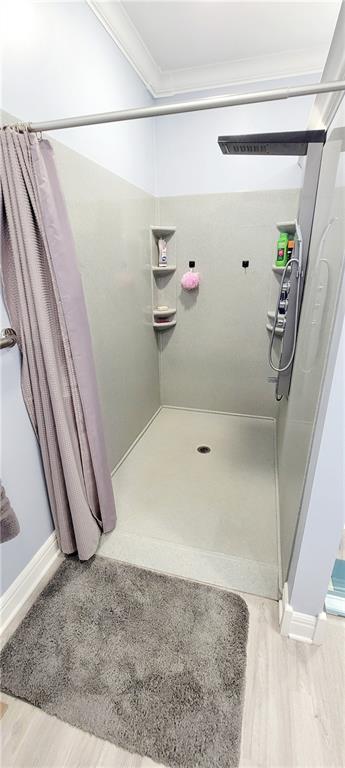 bathroom with walk in shower, wood-type flooring, and crown molding