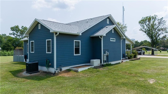 rear view of house with central AC, a yard, and a carport