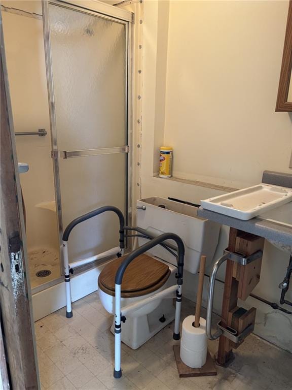 bathroom featuring a shower with door and toilet