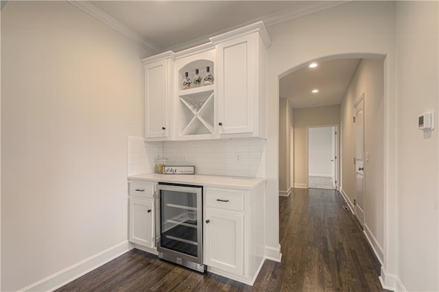 bar featuring white cabinetry, beverage cooler, dark hardwood / wood-style floors, decorative backsplash, and ornamental molding