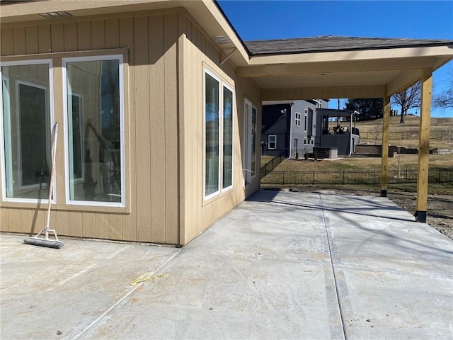 view of home's exterior with a patio, a shingled roof, and fence