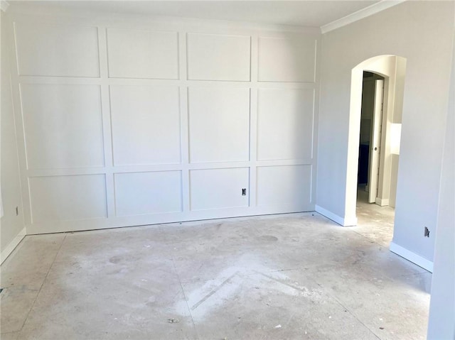 interior space with ornamental molding, arched walkways, a decorative wall, baseboards, and concrete flooring