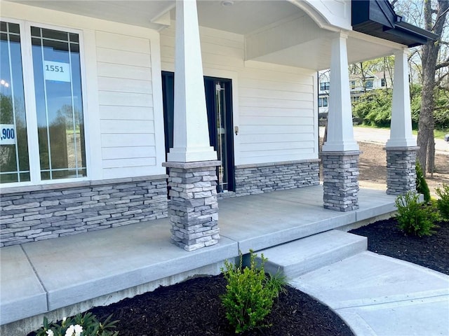entrance to property featuring a porch and stone siding