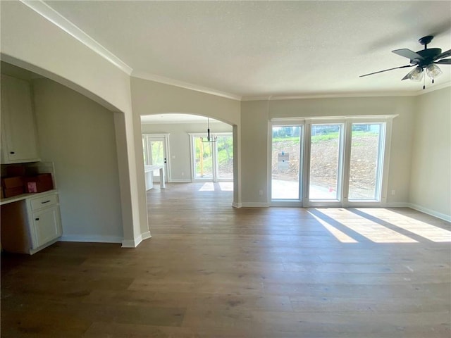 unfurnished living room with arched walkways, a healthy amount of sunlight, and wood finished floors