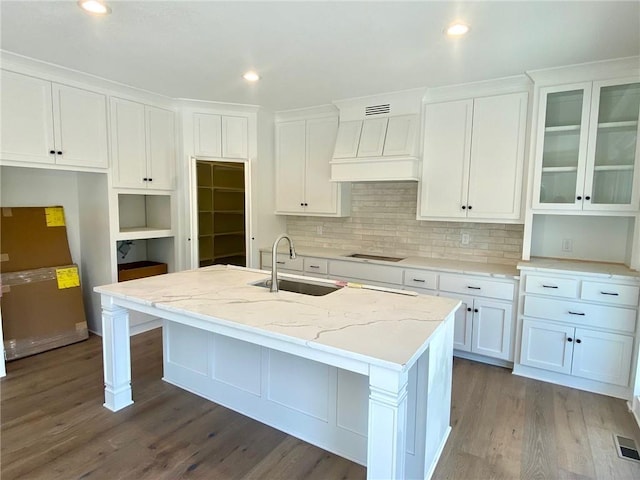 kitchen with premium range hood, white cabinetry, and a sink