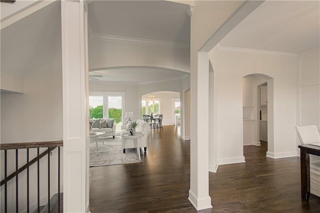 corridor with baseboards, wood finished floors, arched walkways, and crown molding