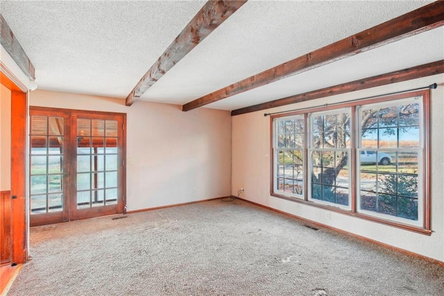 spare room with beamed ceiling, carpet floors, and a textured ceiling