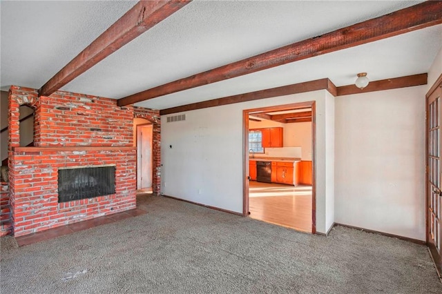 unfurnished living room with a brick fireplace, beamed ceiling, a textured ceiling, and carpet floors