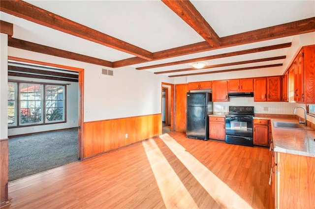 kitchen with beam ceiling, sink, black appliances, and light hardwood / wood-style flooring