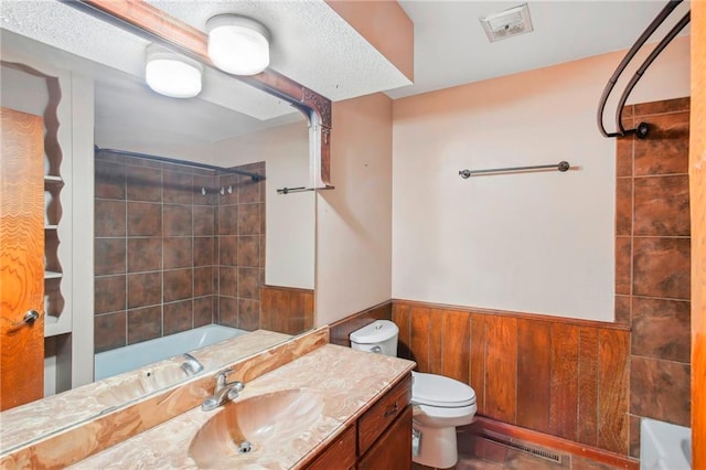 full bathroom featuring wood walls, toilet, vanity, and tiled shower / bath