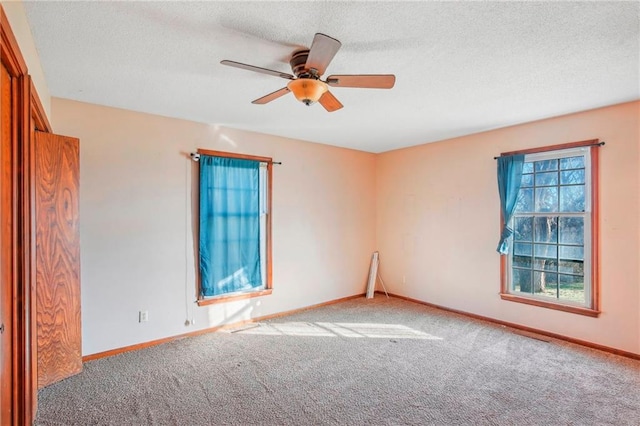 carpeted spare room with a textured ceiling and ceiling fan