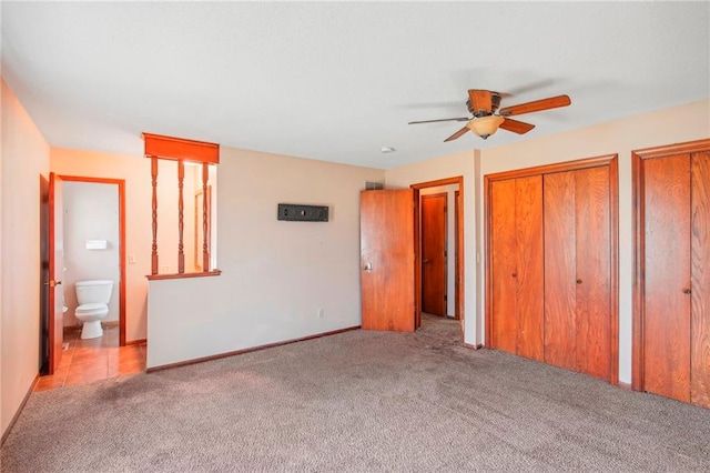 unfurnished bedroom with connected bathroom, light carpet, two closets, and ceiling fan