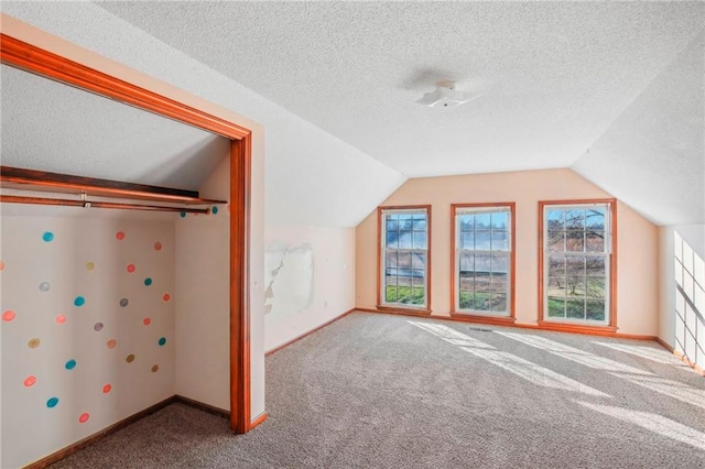 additional living space with a textured ceiling, carpet flooring, and vaulted ceiling