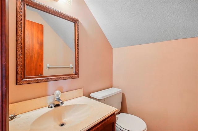 bathroom with vanity, a textured ceiling, toilet, and vaulted ceiling