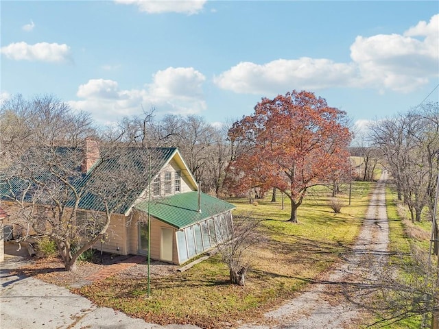 view of side of home featuring a rural view, a lawn, and a sunroom