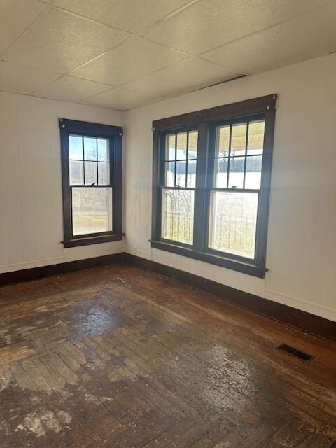 unfurnished room with hardwood / wood-style flooring and a drop ceiling