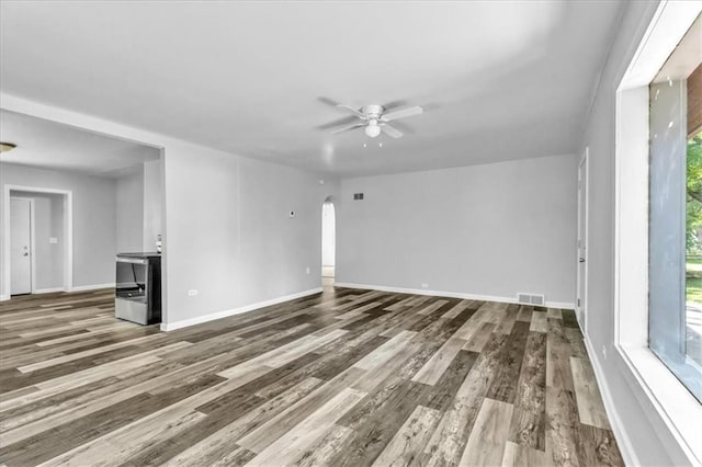 9043 Walnut St, Kansas City, MO 64114 - unfurnished living room with ceiling fan, wood finished floors, arched walkways, and baseboards