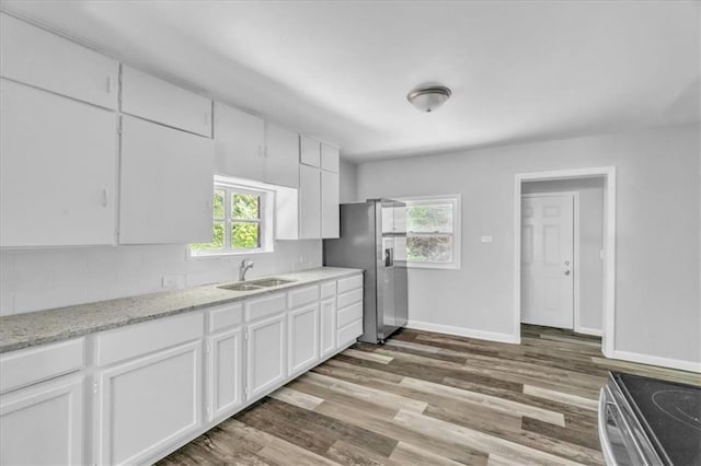 9043 Walnut St, Kansas City, MO 64114 - kitchen featuring a sink, white cabinets, stainless steel appliances, baseboards, and wood finished floors