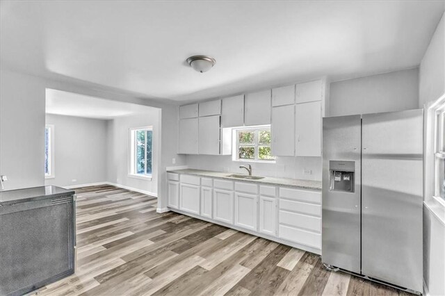 9043 Walnut St, Kansas City, MO 64114 - kitchen featuring stainless steel fridge with ice dispenser, light countertops, light wood-style floors, and white cabinetry