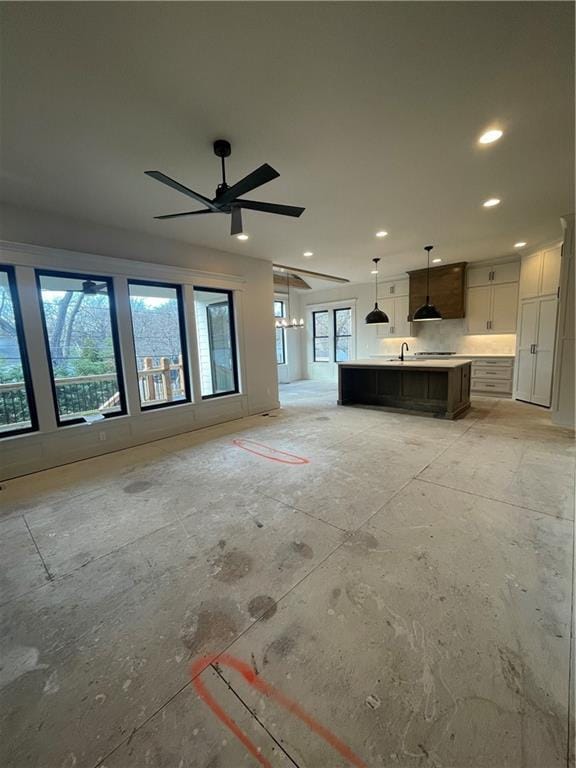 unfurnished living room with sink, a healthy amount of sunlight, and ceiling fan