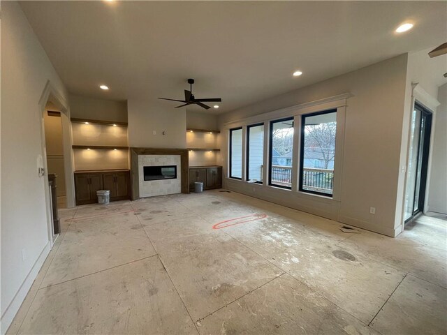 unfurnished living room featuring ceiling fan and a tiled fireplace