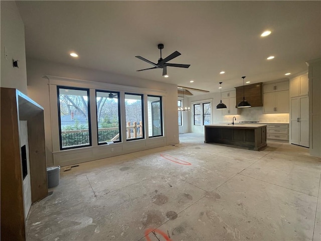 unfurnished living room featuring ceiling fan, sink, and a healthy amount of sunlight