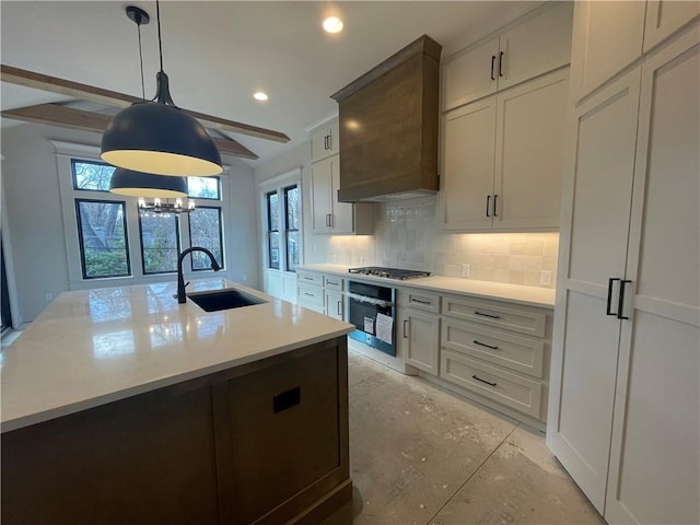 kitchen featuring appliances with stainless steel finishes, tasteful backsplash, sink, white cabinets, and a kitchen island with sink