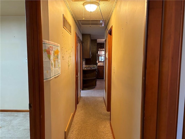 hall featuring a textured ceiling, light colored carpet, and ornamental molding