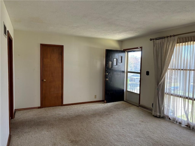 entrance foyer featuring a textured ceiling and light carpet