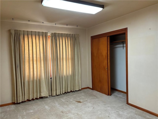 unfurnished bedroom with light colored carpet and a closet