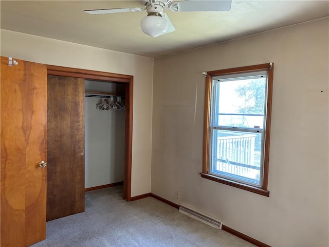 unfurnished bedroom featuring light carpet, a closet, ceiling fan, and baseboard heating