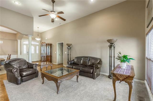 living room with ceiling fan, decorative columns, and a high ceiling