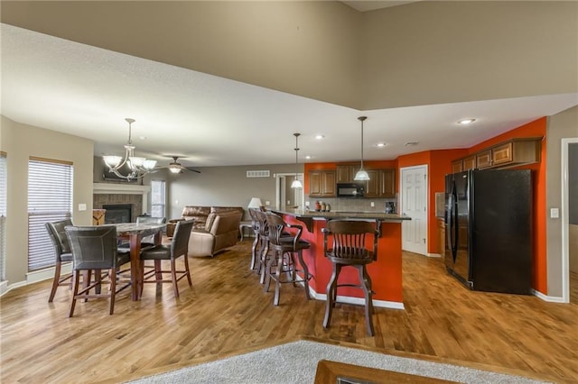 kitchen featuring a breakfast bar, hanging light fixtures, light hardwood / wood-style flooring, and black appliances