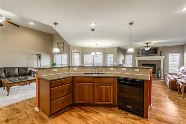 kitchen featuring hanging light fixtures, black dishwasher, sink, and a center island with sink