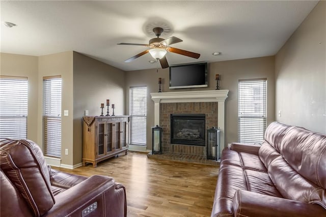 living room with ceiling fan, a fireplace, and light hardwood / wood-style floors