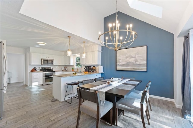 dining room with a skylight, sink, an inviting chandelier, light hardwood / wood-style flooring, and high vaulted ceiling