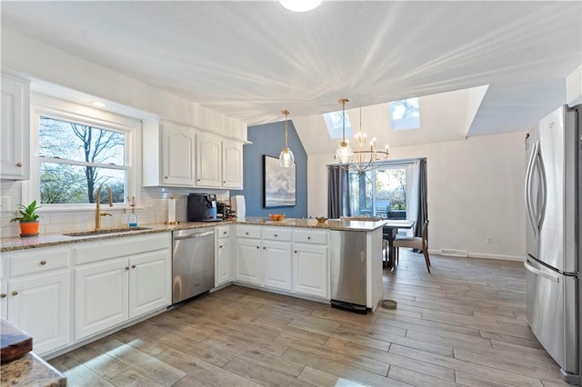 kitchen featuring sink, stainless steel appliances, kitchen peninsula, decorative backsplash, and white cabinets