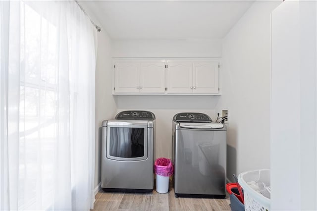 laundry room with cabinets, light hardwood / wood-style flooring, and washing machine and clothes dryer