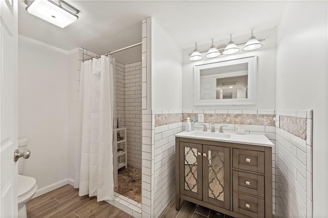 bathroom with a shower with shower curtain, vanity, wood-type flooring, tile walls, and toilet