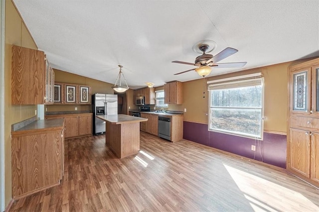 kitchen featuring ceiling fan, a center island, hanging light fixtures, appliances with stainless steel finishes, and hardwood / wood-style flooring