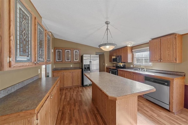 kitchen with hardwood / wood-style floors, a kitchen island, stainless steel appliances, and decorative light fixtures