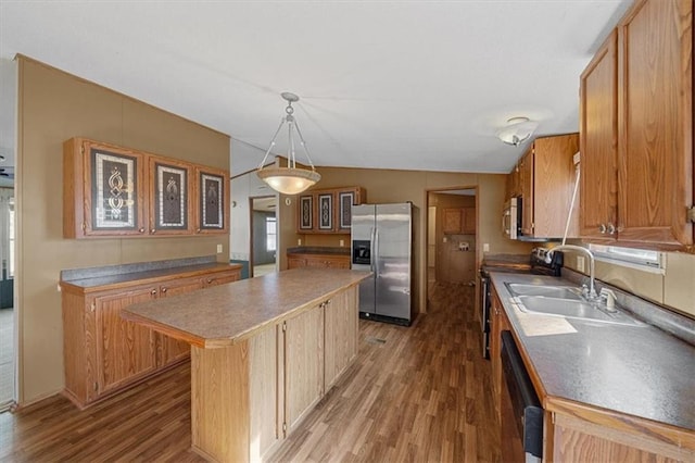 kitchen featuring a center island, sink, vaulted ceiling, appliances with stainless steel finishes, and decorative light fixtures