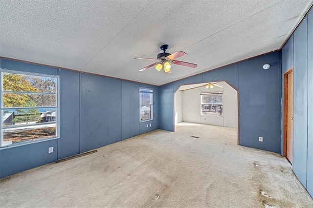 empty room featuring a textured ceiling, ceiling fan, light carpet, and vaulted ceiling