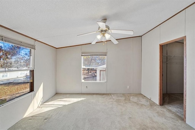 empty room with lofted ceiling, ceiling fan, light carpet, and a textured ceiling