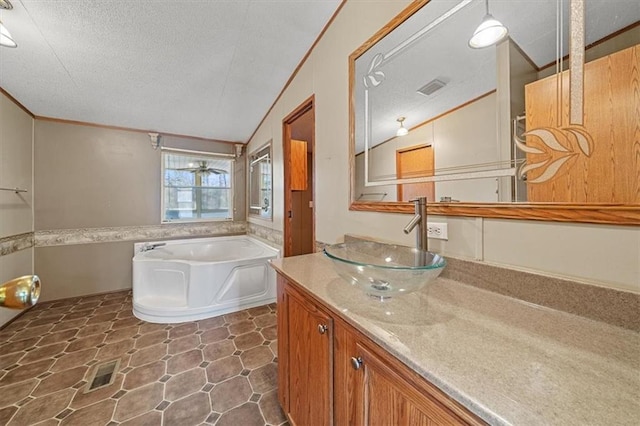 bathroom featuring a textured ceiling, vanity, a bath, and vaulted ceiling