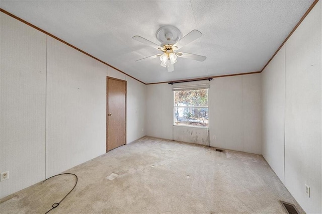 spare room with a textured ceiling, ceiling fan, crown molding, and light carpet