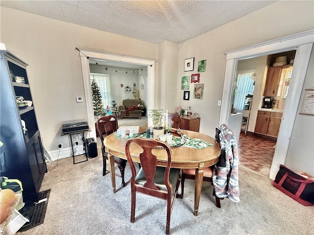 carpeted dining room featuring a textured ceiling